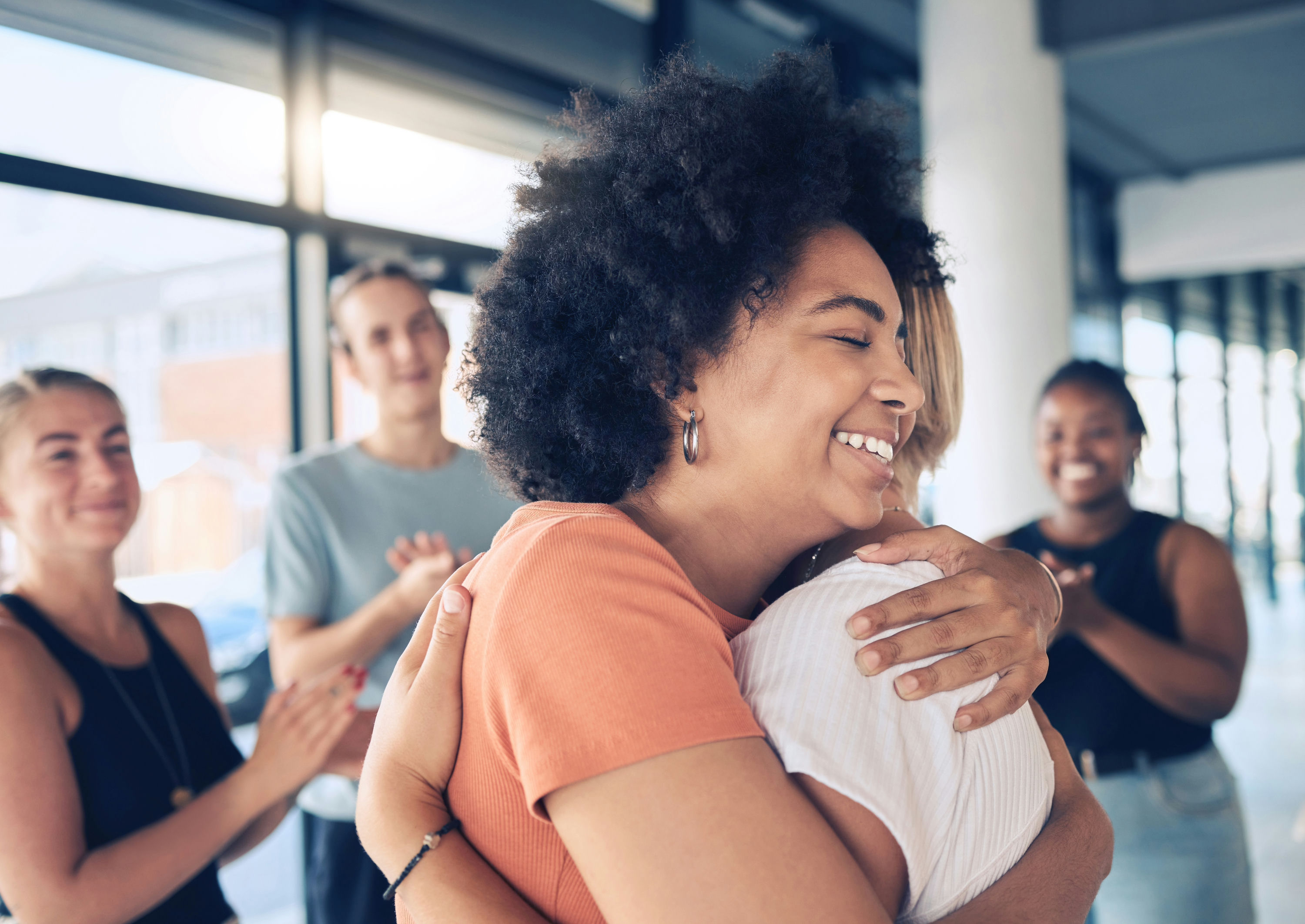 Group of individuals hugging during ACT therapy session in a rehab setting