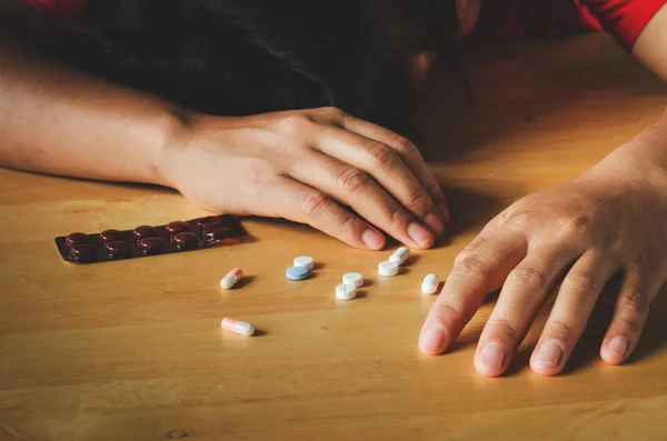 Individual leaning on a table surrounded by scattered Xanax pills, struggling with addiction