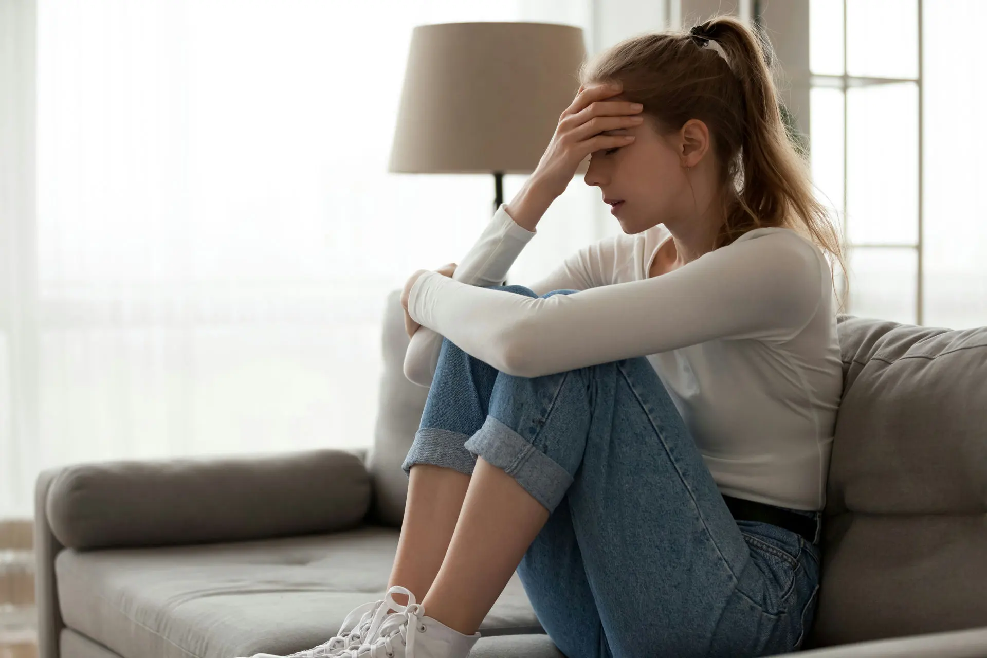 Woman sitting on a couch experiencing Xanax withdrawal symptoms